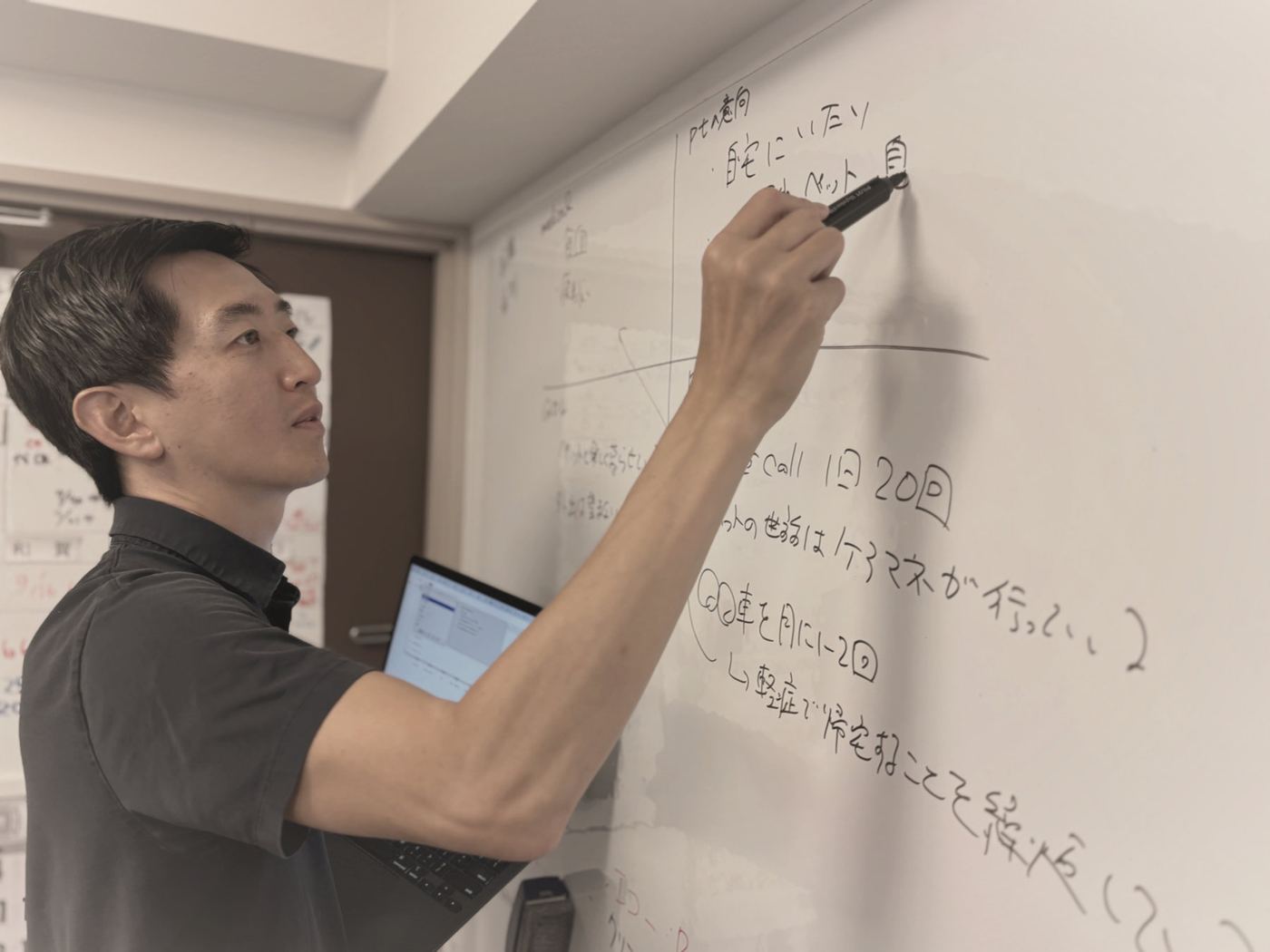ホワイトボードに書きながら、診療の進め方を考える院長